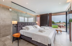 Une chambre moderne avec un grand lit, une douche en verre et une vue sur l’extérieur.