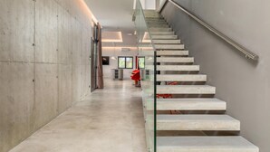 Un interior moderno con pared de hormigón, escalera de cristal y diseño minimalista.