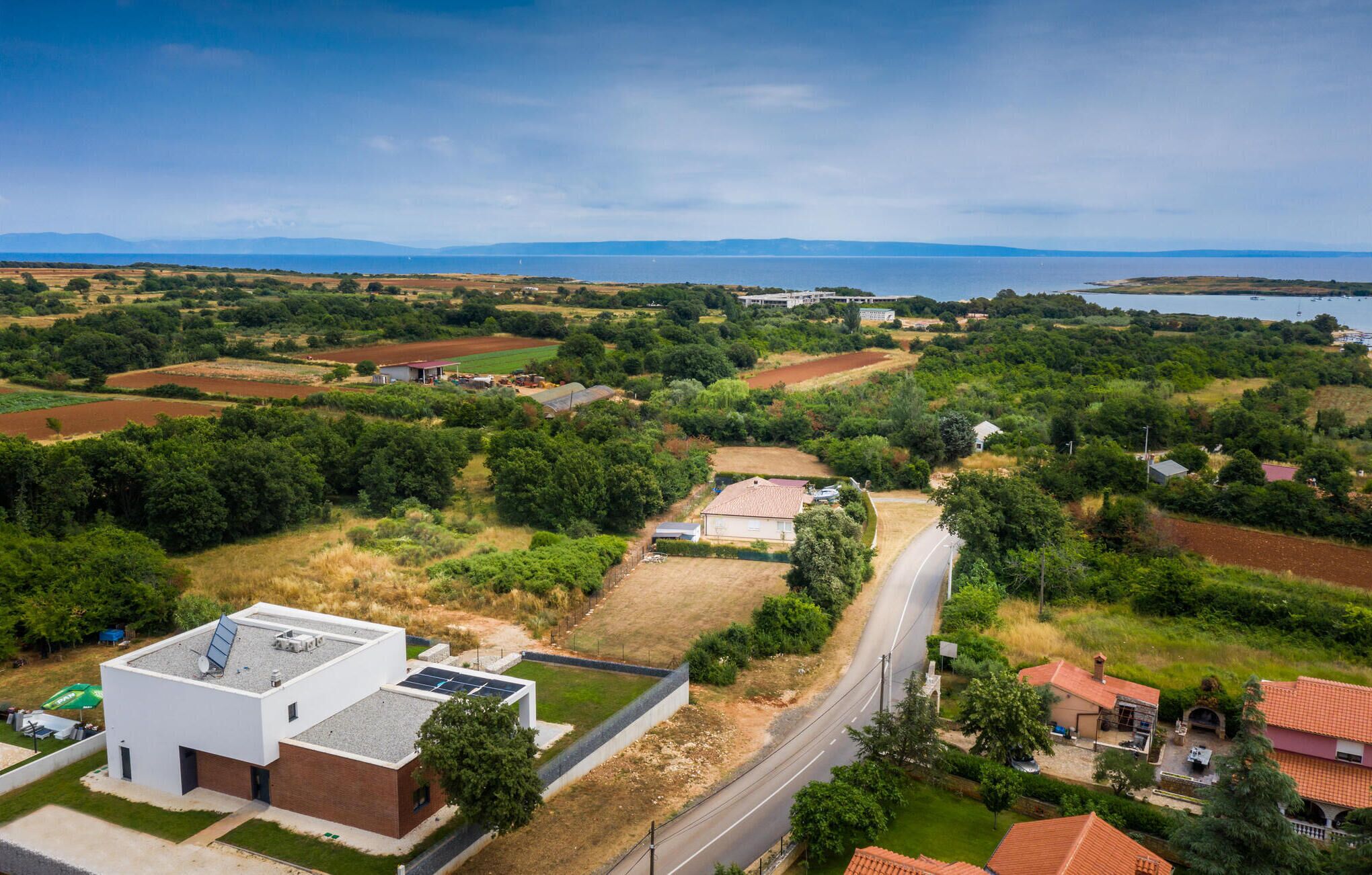 A residential area with houses, a road, and a body of water in the background.