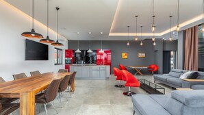 Una cocina moderna con armarios rojos, una isla central e iluminación colgante.