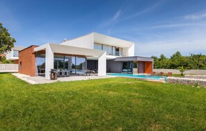 Une maison moderne à deux étages, dotée d’une piscine, d’un espace extérieur aménagé et d’une pelouse bien entretenue.