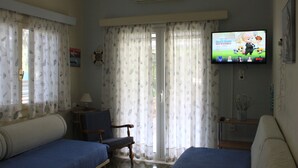 Een hotelkamer met twee bedden, een televisie, een stoel en een tafeltje.