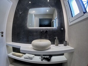 A modern bathroom with a curved white vanity, a large mirror, and a round sink.