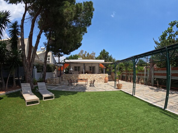 A house with a patio area featuring outdoor furniture, a stone wall, and a pergola.