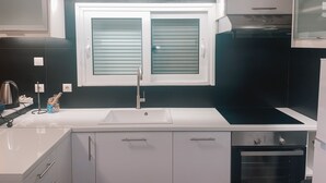 Een moderne keuken met een wit aanrecht, een roestvrijstalen spoelbak en een inbouwoven.