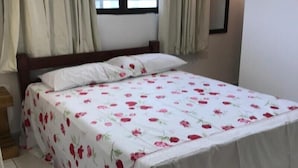 Une chambre à coucher avec un lit, des rideaux, une fenêtre et une lampe fixée au mur.
