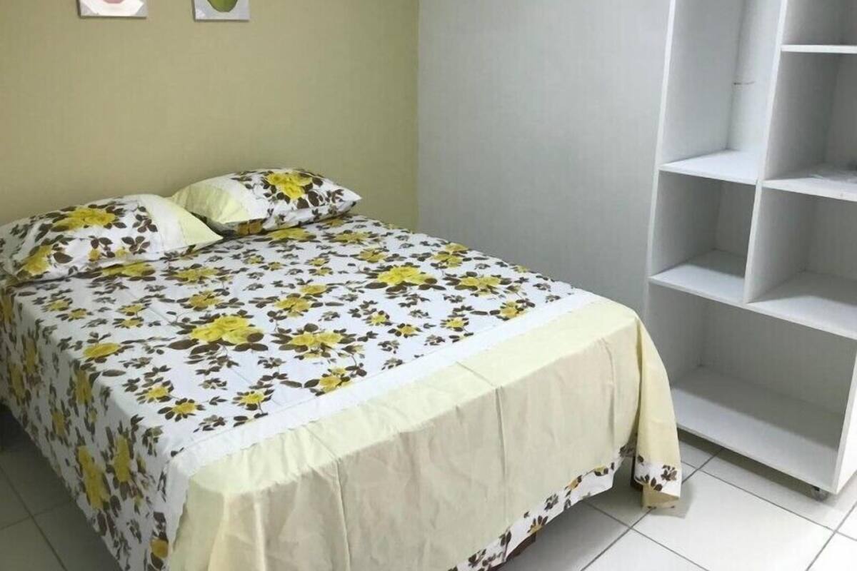 A bedroom with a bed, a white wardrobe, and two framed pictures on the wall.