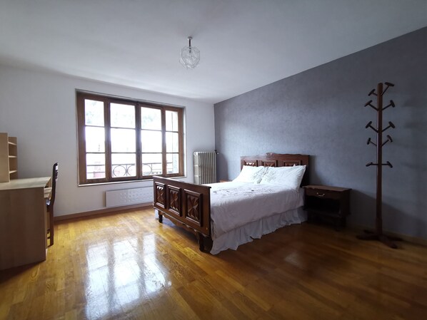 Cozy retreat with a large window, wooden bed, and bedside table.