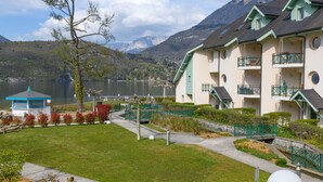 Un hôtel doté de nombreux balcons, d’une pelouse bien entretenue et offrant une vue sur les montagnes et un lac.
