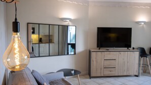 Un salon moderne avec un canapé, un téléviseur et un meuble en bois.