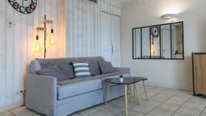Un salon avec un canapé, une table basse, une horloge murale et un miroir.