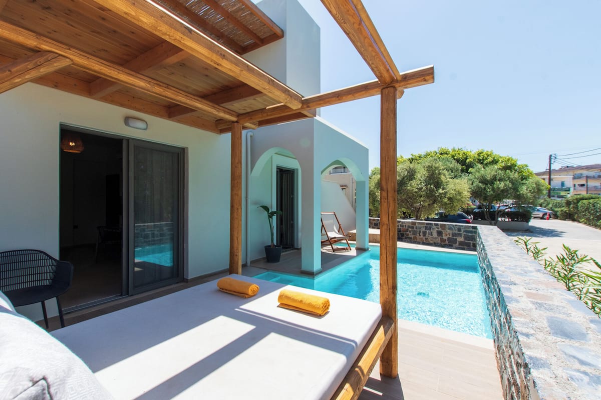 Un espace aménagé au bord de la piscine, comprenant une pergola en bois, un fauteuil et une chaise longue.