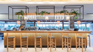 Uma área de bar moderna com banquetas de madeira, balcão de madeira e plantas.