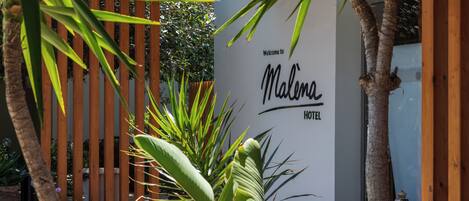 Uma pérgola de madeira com uma placa que diz 'Malina Hotel' ao fundo.