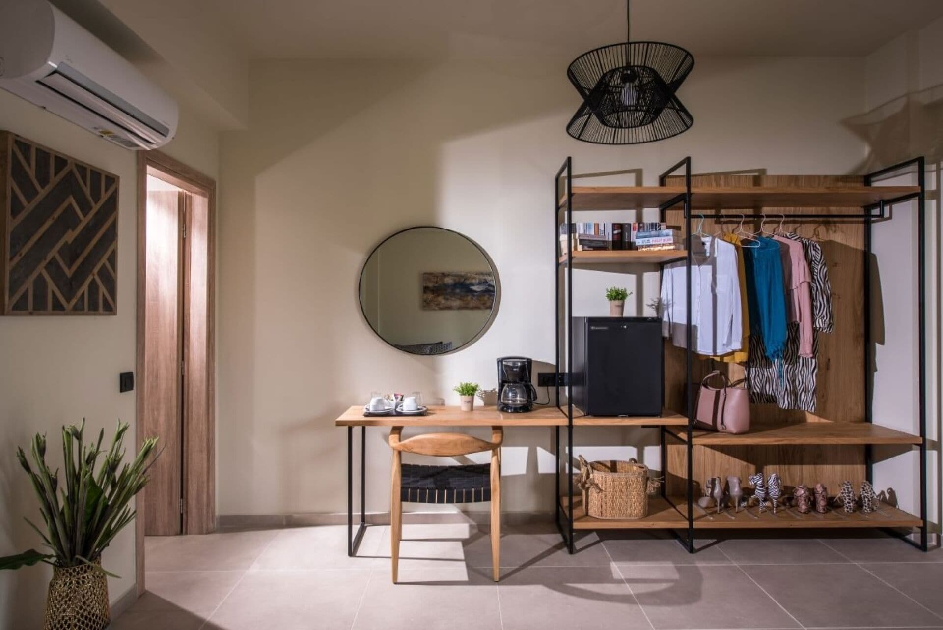Une pièce de taille modeste, équipée d’un bureau, d’une chaise et d’une armoire où sont suspendus des vêtements.