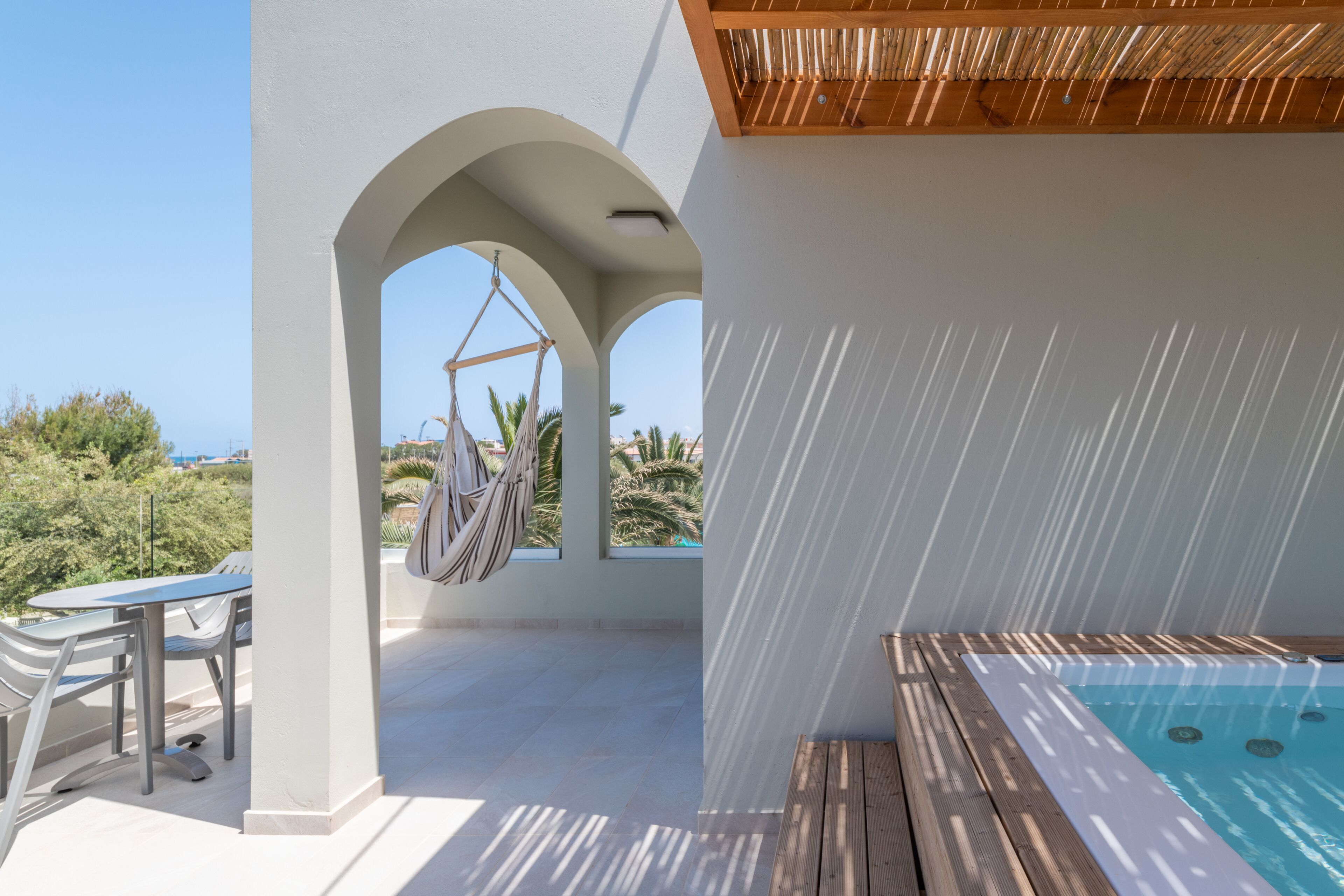Eine Dachterrasse mit Whirlpool, einer Hängematte und einem Tisch mit Stühlen.