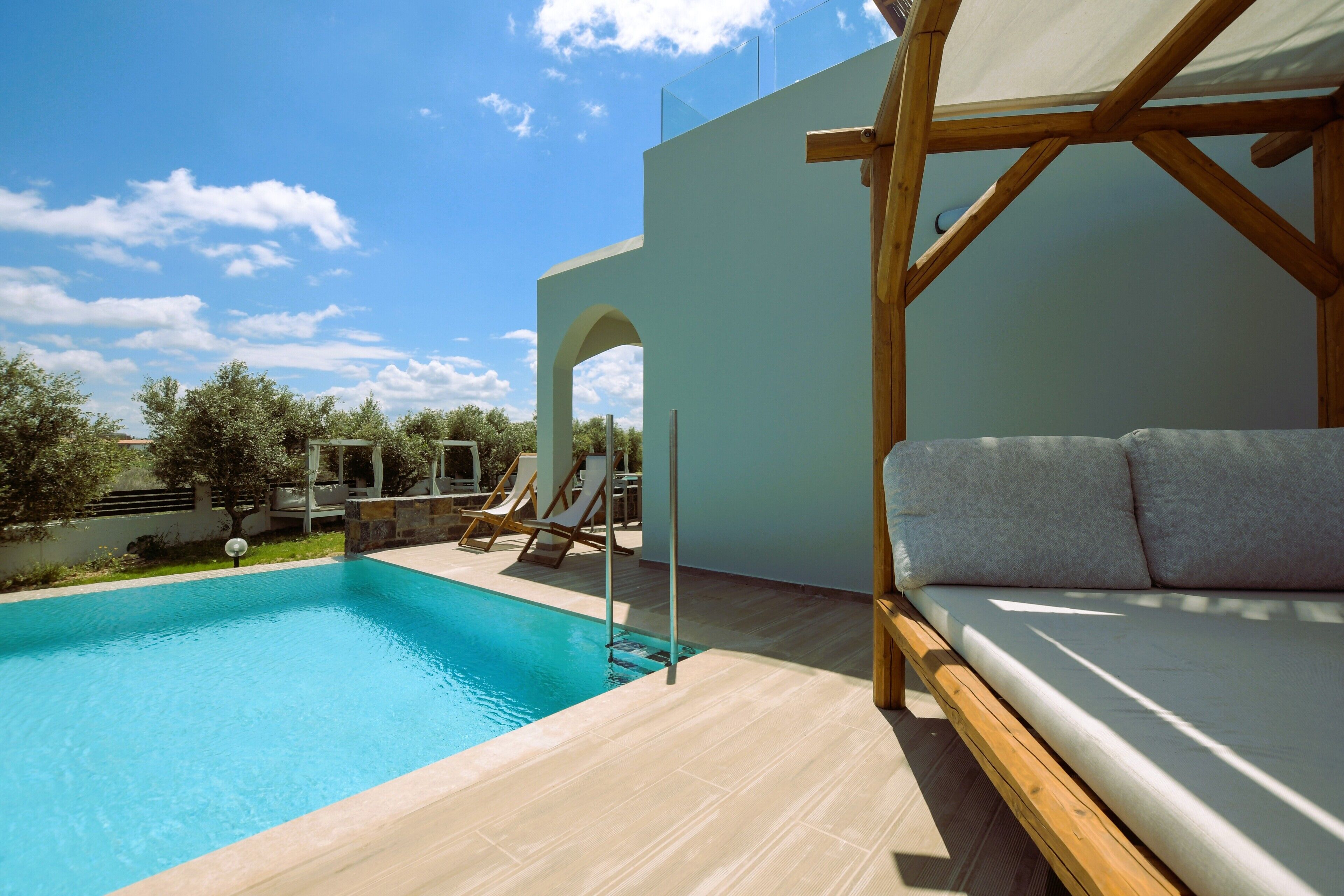 Un área de piscina moderna con cubierta de madera, un sillón de playa y un sofá.
