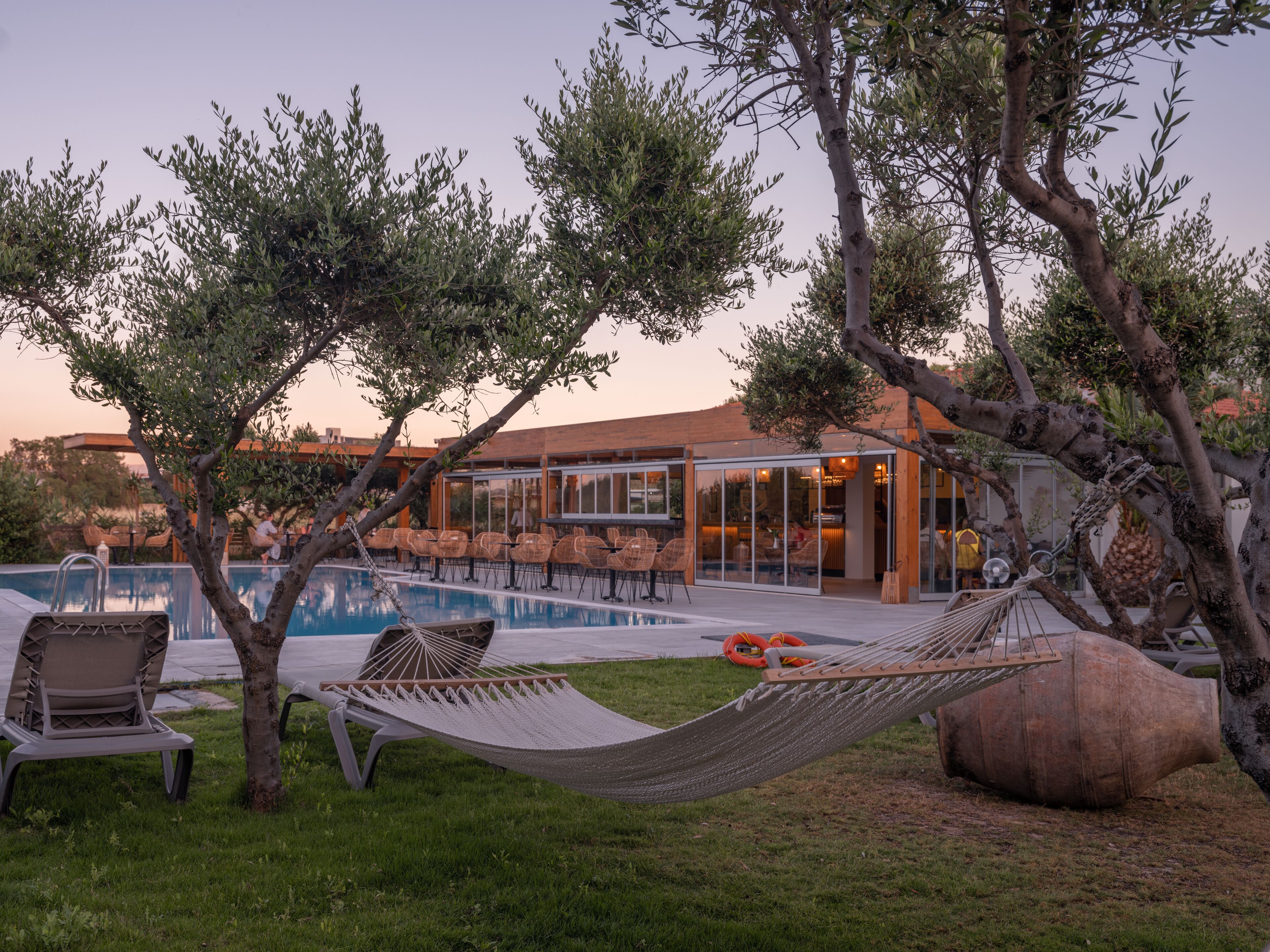 A pool area with lounge chairs, a hammock, and a large rock.