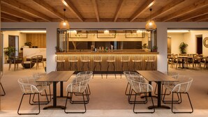 Uma área de bar moderna com teto de madeira, cadeiras de vime e uma mesa de madeira comprida.