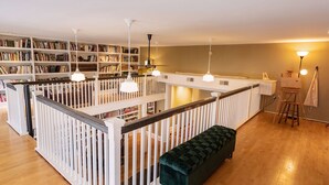 Et bibliotek med træbogreoler, et centralt læseområde med en bænk og et staffeli.