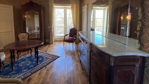 A room with a wooden floor, a dining table, a sofa, a chair, a large mirror, and a patterned wallpaper. - Great château close to Bourges  for 15 people (Blet)