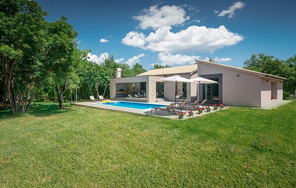 Una casa moderna amb piscina, mobiliari exterior i jardí.