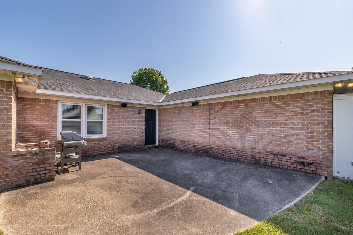 A single-story brick house with a covered patio, a door, and a window.