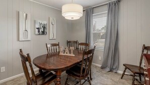 A dining room with a wooden table, six chairs, a chandelier, and a window with curtains. - Walk to Stadium! Modern Home + Free Parking (Tuscaloosa)