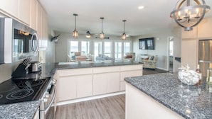 A modern kitchen with granite countertops, stainless steel appliances, and pendant lighting. - Harbor Point Ocean Front Beach Estate (Saint Helena Island)