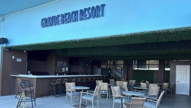 Utomhusområdet vid Grande Beach Resort har bord och stolar, en bar och en trappa som leder upp till en övre våning.