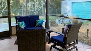Un patio techado con mobiliario de mimbre y vistas al jardín trasero.