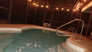 Un jacuzzi con escalera metálica, rodeado por una terraza empedrada.