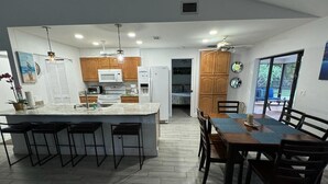 Una cocina moderna con una isla central, taburetes de bar y un comedor con mesa y sillas.