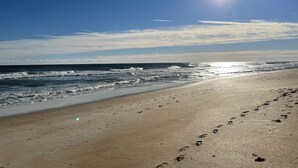 A beach with footprints leading to the water, a clear sky, and the sun shining. - Ocean Front Condo in Ormond By The Sea ( Ormond Beach )  (Ormond Beach)