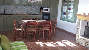A kitchen with green cabinets, a dining table with chairs, a microwave, and a stove.