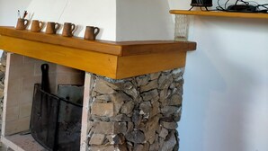 A stone fireplace with a wooden mantel, a TV on a shelf above, and decorative wall art.