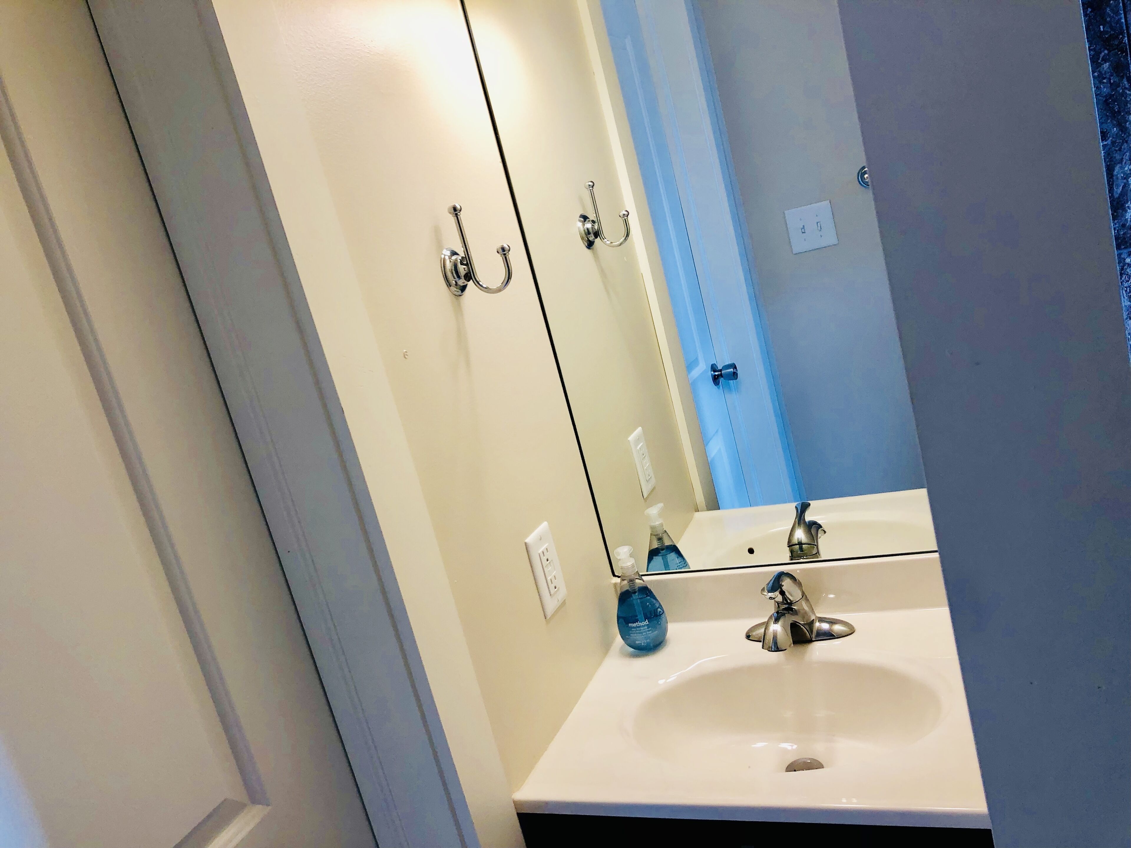 Un baño con un lavamanos blanco, un espejo y una puerta azul.