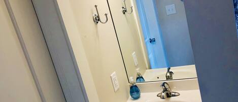Un baño con un lavamanos blanco, un espejo y una puerta azul.