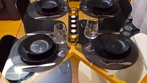 A dining table set for four with black plates and cutlery, a microwave, and a coffee maker on the table. - l'Art de l'eau beach studio on private property (NEUFCHÂTEL-HARDELOT)