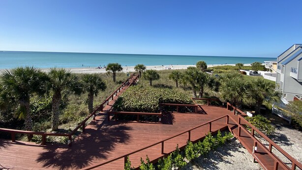 Une terrasse en bois offrant une vue sur la plage et l’océan.