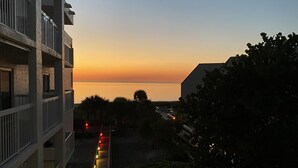 Un immeuble doté d’un balcon donnant sur un coucher de soleil.