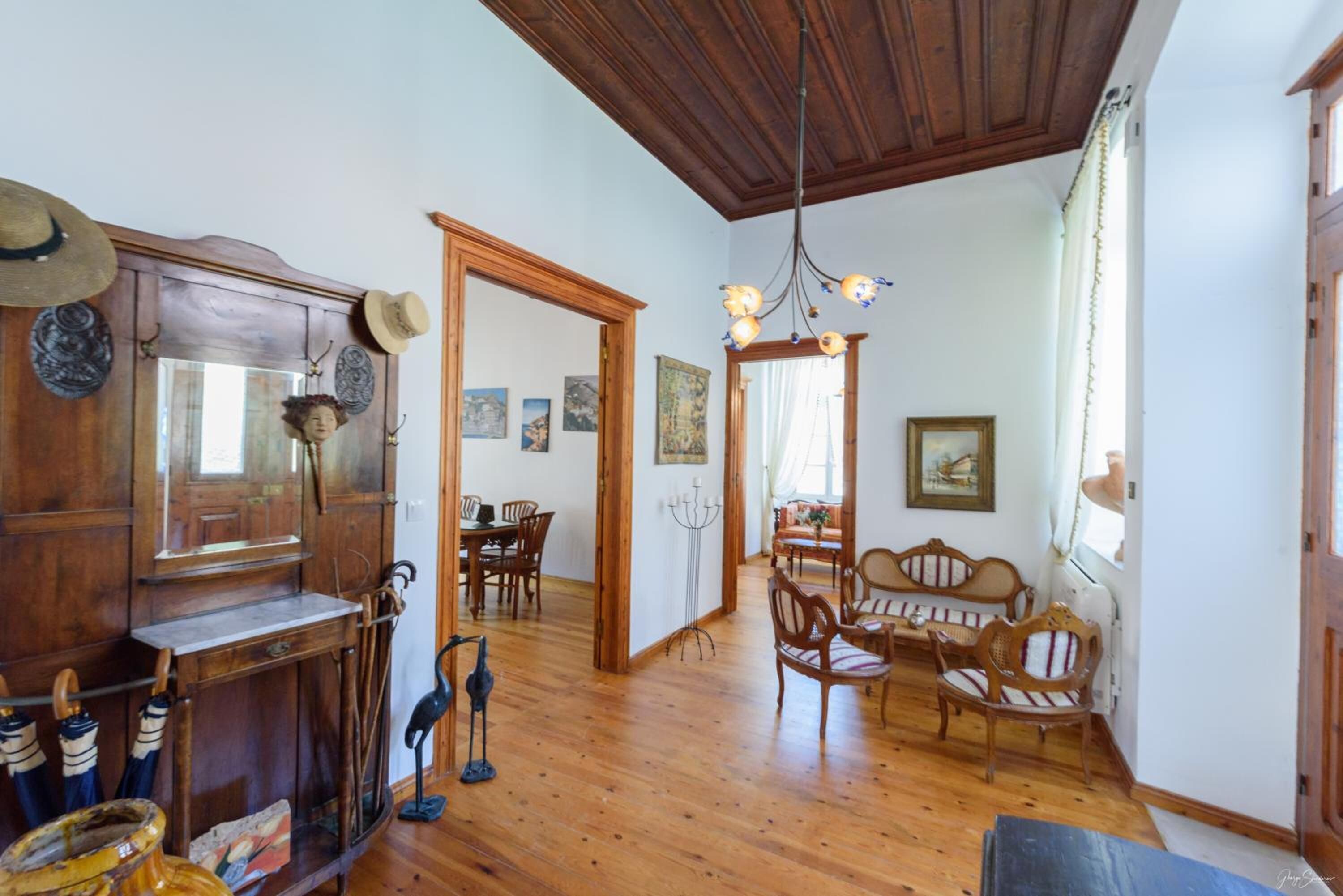 A spacious room with wooden flooring, a dining area with chairs and a table, and a seating area with a sofa and chairs.