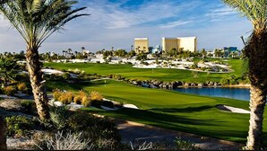 A golf course with sand bunkers, a water hazard, and palm trees. - Spacious 2-Bedroom Condo w/ Kitchen, Pool, 24/7 Free Shuttle to Strip (Las Vegas)