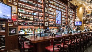 A bar with a long counter, multiple shelves of liquor bottles, and several televisions displaying news. - Spacious 2-Bedroom Condo w/ Kitchen, Pool, 24/7 Free Shuttle to Strip (Las Vegas)