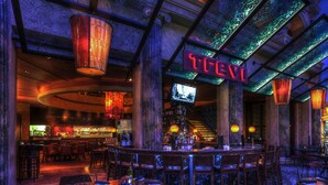 A bar area with a neon sign, bar stools, and a television screen. - Spacious 2-Bedroom Condo w/ Kitchen, Pool, 24/7 Free Shuttle to Strip (Las Vegas)