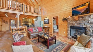 A spacious living area with a high ceiling, wooden walls, a stone fireplace, and a cozy seating arrangement. - Booking Summer! 4 Masters Family Friendly Hot Tub Fire Pit Secluded Yard (Sevierville)