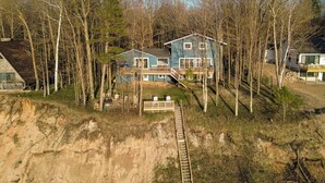 Una casa con terraza de madera, una escalera y un sendero de tierra que lleva a ella.