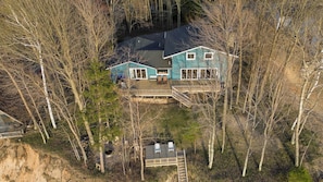 A two-story house with a deck, surrounded by trees.