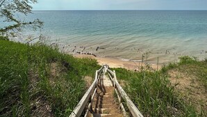 Una escalera de madera que baja a una playa con cielos despejados.