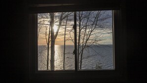 Una ventana con vistas a árboles y una masa de agua al atardecer.